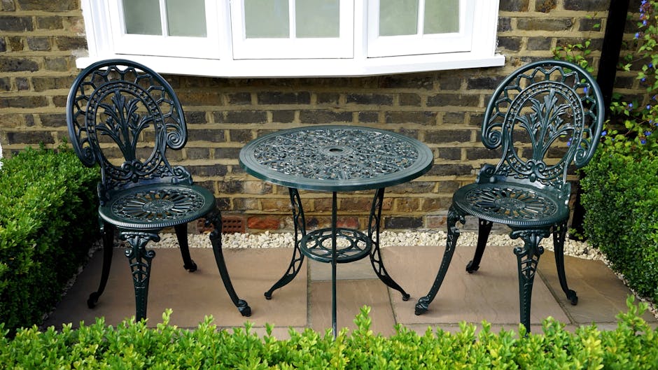 A detailed view of a small front garden showcasing a well-maintained lawn with neatly trimmed grass, bordered by a wooden pathway leading to the entrance of a house. The garden includes a variety of p