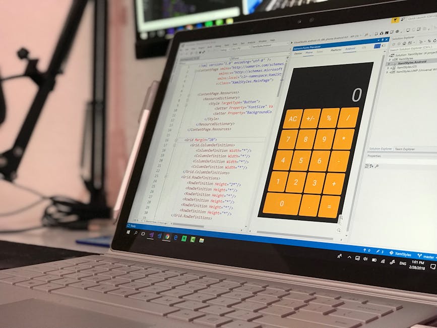 A close-up view of a laptop positioned on a desk, displaying a screen with lines of code in a text editor on the left side and a large calculator app with orange buttons on the right side. The code ap